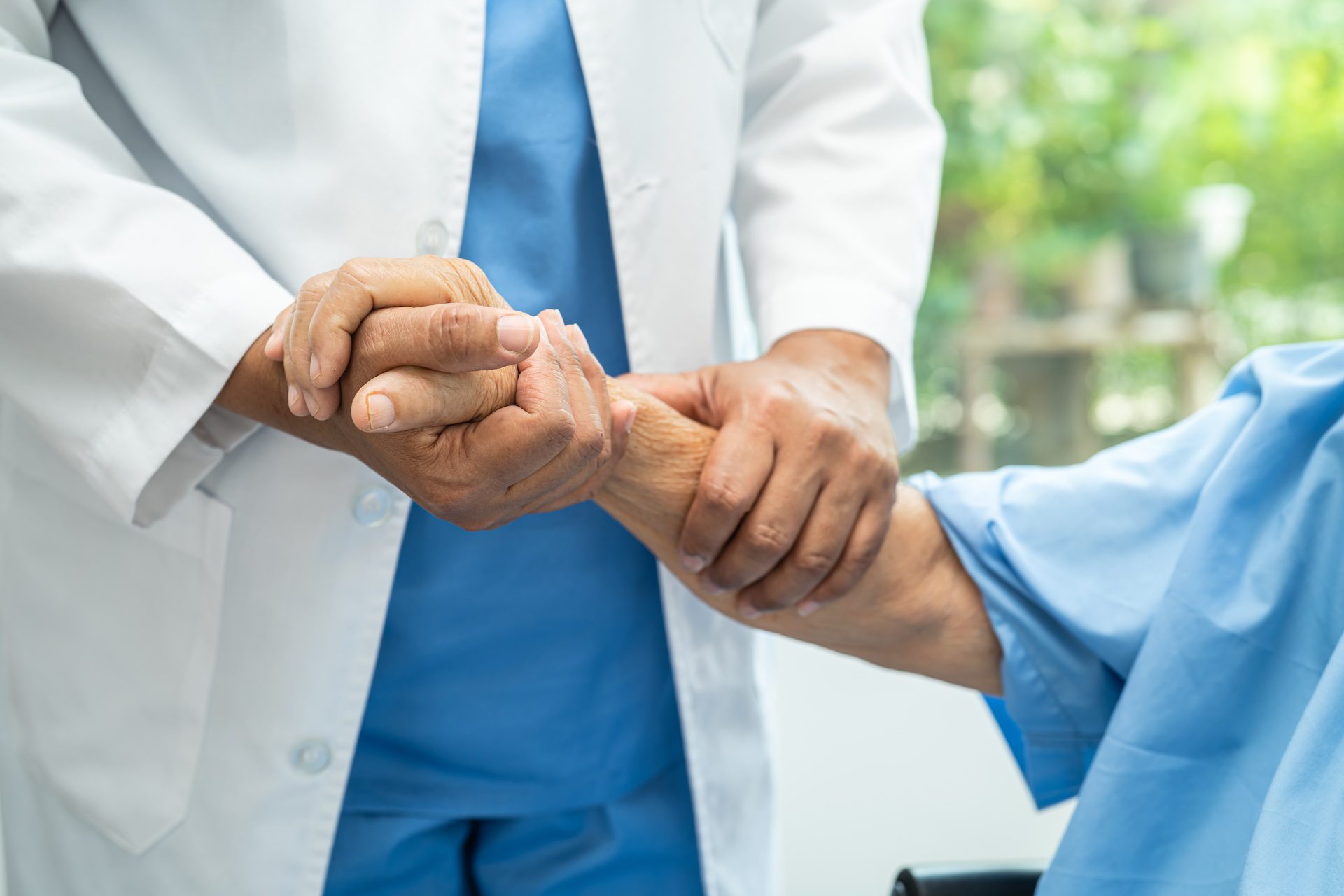 Medical professional and patient holding hands