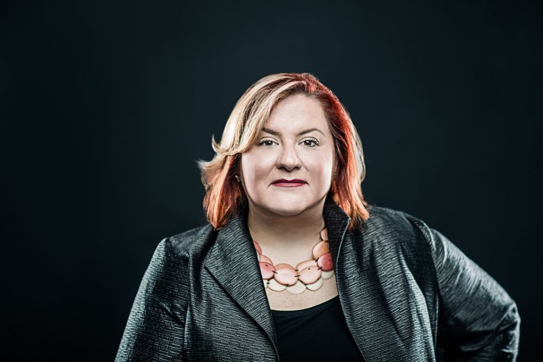 Woman wearing a blazer against a dark background